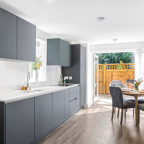 Open-plan kitchen and dining area with modern cabinetry, wooden flooring and natural light