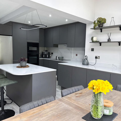 Modern grey kitchen with a white quartz island, open shelving and dining area