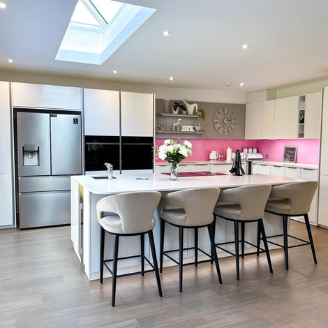 White kitchen island with a black sink and chrome tap under recessed lighting