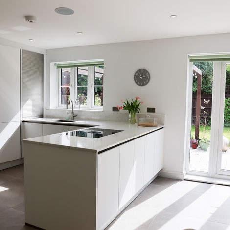 Open-plan white kitchen with garden doors, handleless cabinetry and integrated appliances