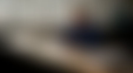 En ingenjör står vid ett arbetsbord i industrimiljö och utför noggranna mätningar på en metallcylinder.