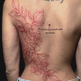 Tatouage floral rouge dos à Nice au salon La Fratrie.