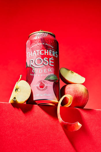 Thatchers Rose Cider bottle with apple pieces on red backdrop, product beverage photography North Yorkshire