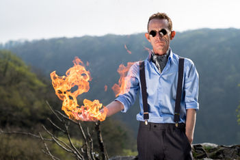 creative portrait of fire-performer holding holding a fire flame in his hand