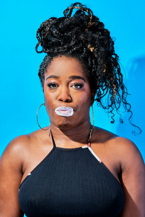 black skin colour model with bubble gum blowing a bubble set on a bold blue backdrop