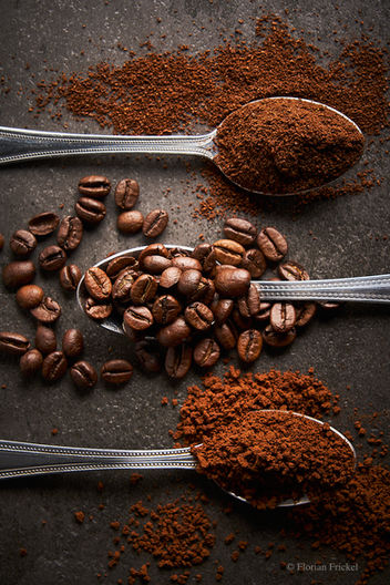three spoons with 3 different types of of coffee, one spoon with coffee ground, one spoon with coffee beans and one spoon with coffee granules 