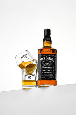 Product photo of Jack Daniels bottle with two stacked glasses on white backdrop, commercial drink photography Harrogate