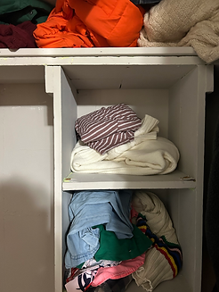 Clothes are placed on the upper shelves in the small closet