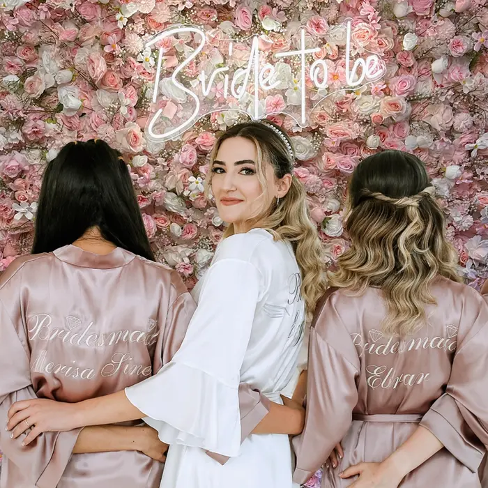 WB Flora ścianka kwiatowa MEADOW w pakiecie z neonem "Bride to be" podczas wesela - panna młoda i druhny na tle ścianki kwiatowej Meadow WB FLORA