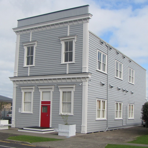 After - same view with exterior restored and repainted beautifully in grey with white trim and a bright red door