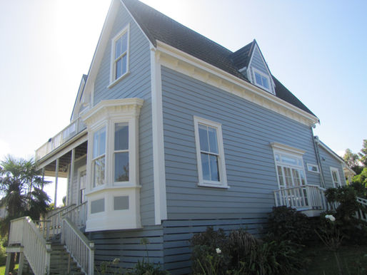 A 2 storey NZ wooden villa with dormer windows, freshly painted in blue/grey with white trim