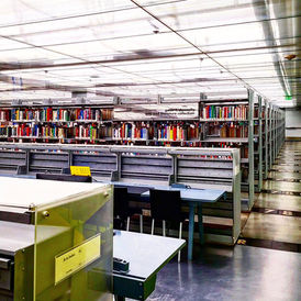 A room lined with metal bookshelves and bright industrial lights