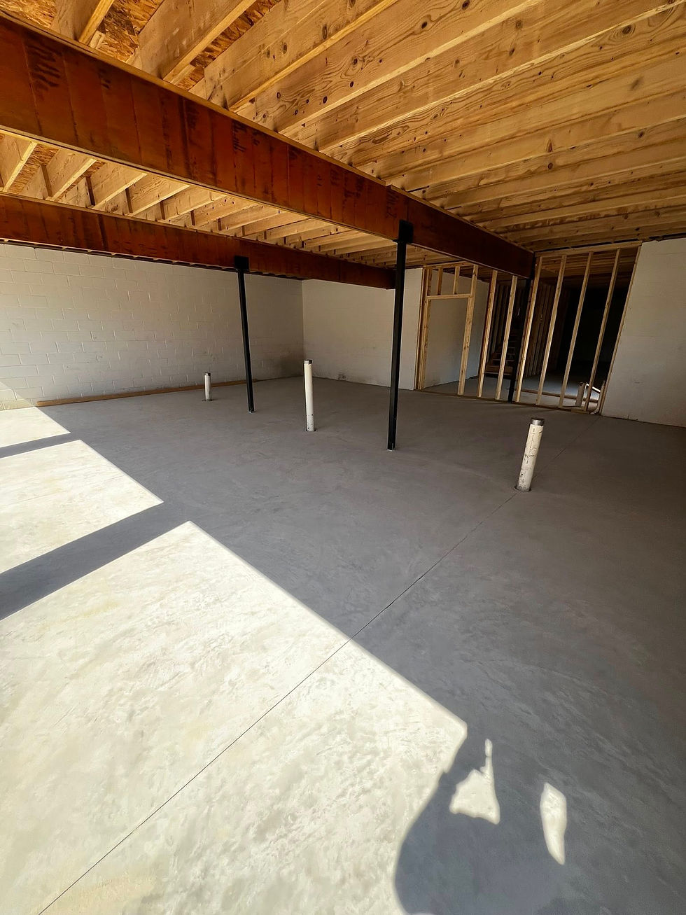 Unfinished basement with poured concrete floor and exposed beams