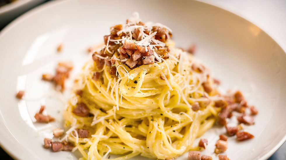 Spaghetti carbonara garnis de lardons et de fromage râpé sur une assiette blanche. Couleurs dorées et ambiance appétissante.