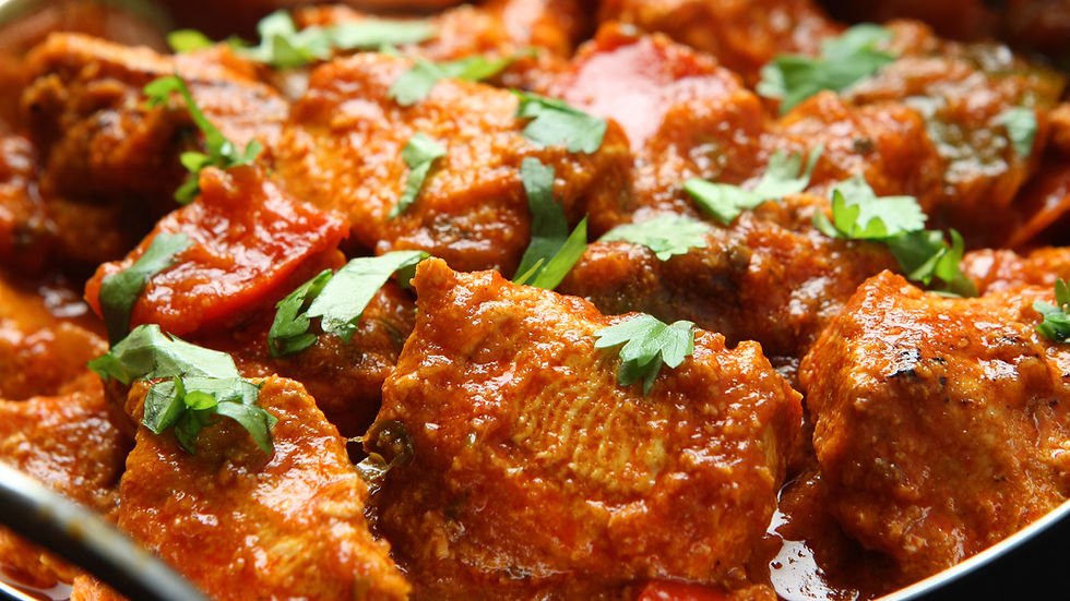 Gros plan d’un curry de poulet rouge, morceaux en sauce garnis de coriandre, dans un plat, ambiance appétissante.