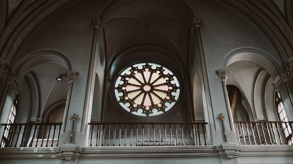 Intérieur d’une église gothique, arches grises et grande rosace colorée au centre, ambiance calme et solennelle.
