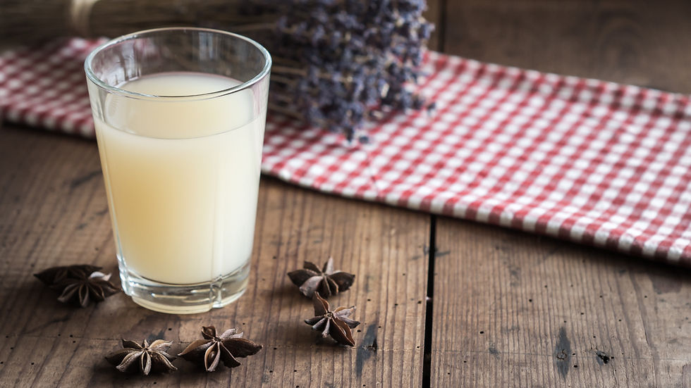 Verre de boisson pâle sur table en bois, avec anis étoilé et torchon vichy rouge, ambiance rustique.