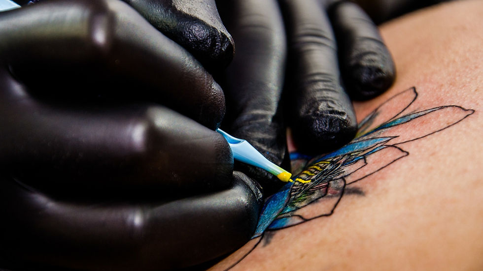 Gros plan sur des mains gantées tatouant une fleur colorée sur la peau. Stylet turquoise, détails bleus et jaunes. Ambiente artistique.