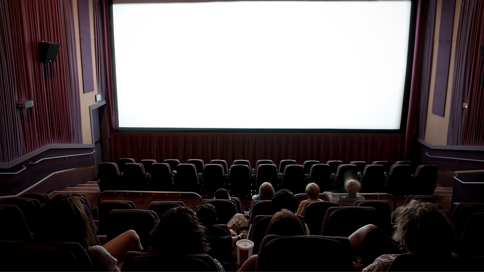 Salle de cinéma sombre avec écran blanc géant, spectateurs assis en silence devant l’écran vide.