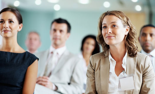 There are two women in the foreground, and other people in the background.
