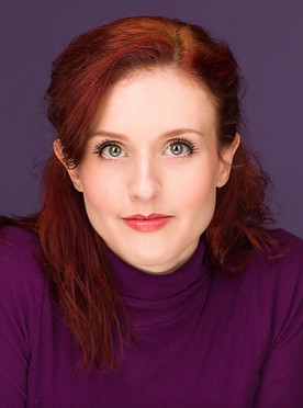 Headshot of Hadley - a red haired woman wearing a purple turtleneck, set against a solid purple backdrop. 