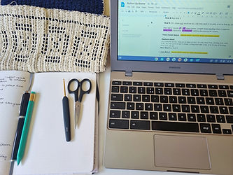 Open laptop with screen showing a pattern part way through being tech edited with an example of filet crochet along with a dotted notebook, pen, pencil and scissors.