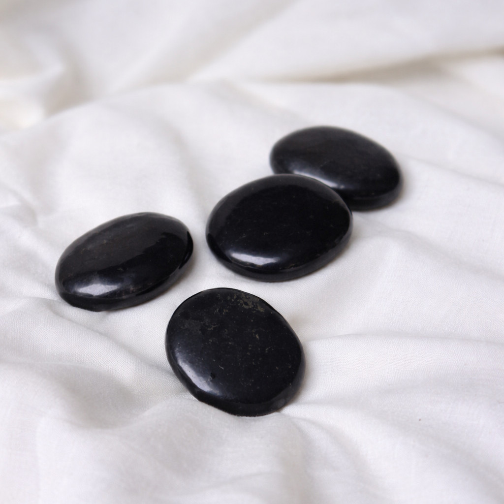 Four black smooth crystals on white fabric
