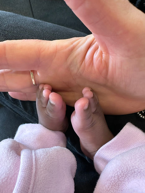 Newborn baby feet next to a hand