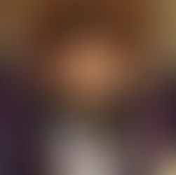 Mädchen steht vor einer lehmverpuzten Wand und lächelt in die Kamera