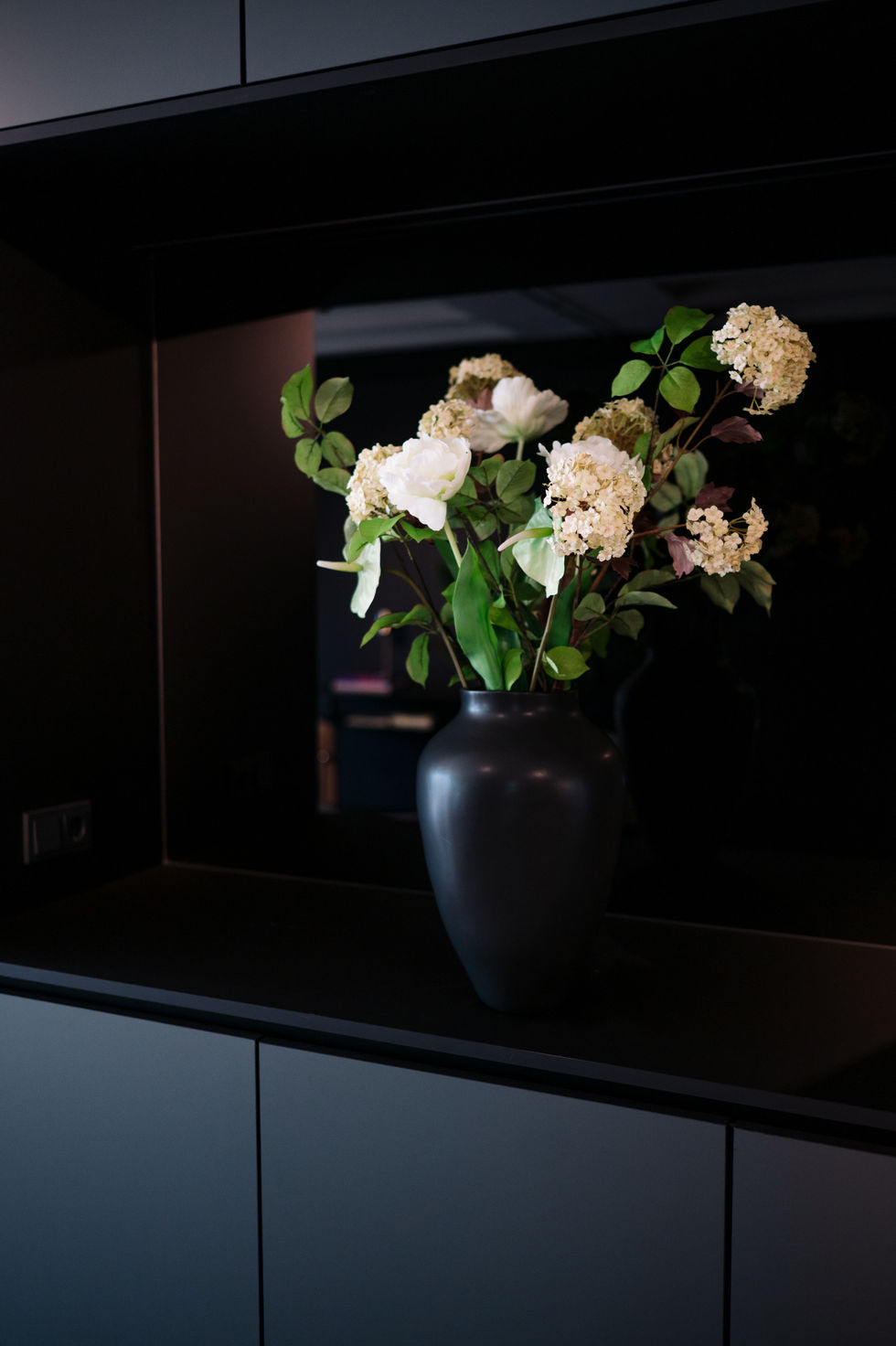 Floral arrangement in a matte black vase styled by a Stockholm interior designer for a boutique office lounge in Frankfurt.