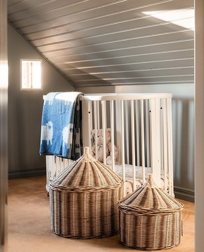 Barnrum med rund spjälsäng och korgar i rotting, inredningsdesign Stockholm