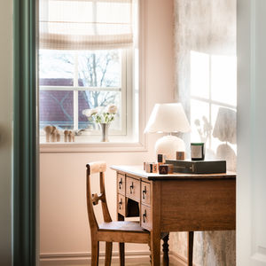 Scandinavian-style workspace corner in a lake house bedroom, featuring vintage wood desk, minimal decor, and soft natural lig