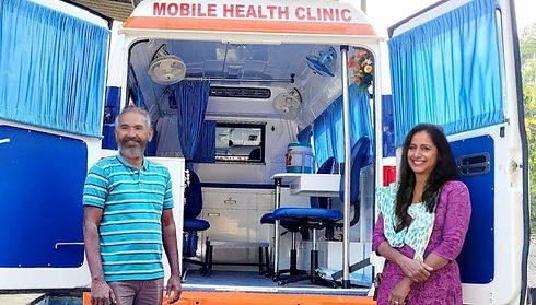 Indian man and woman standing infront of a mobile health clinic