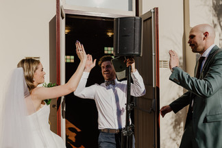 Outside North Perth Town Hall the bride and groom high five their guests as they exit the wedding ceremony