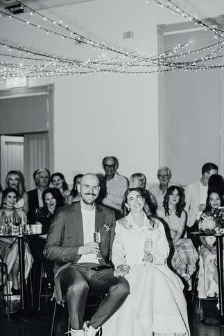 The bride and groom and guests listen to wedding speeches