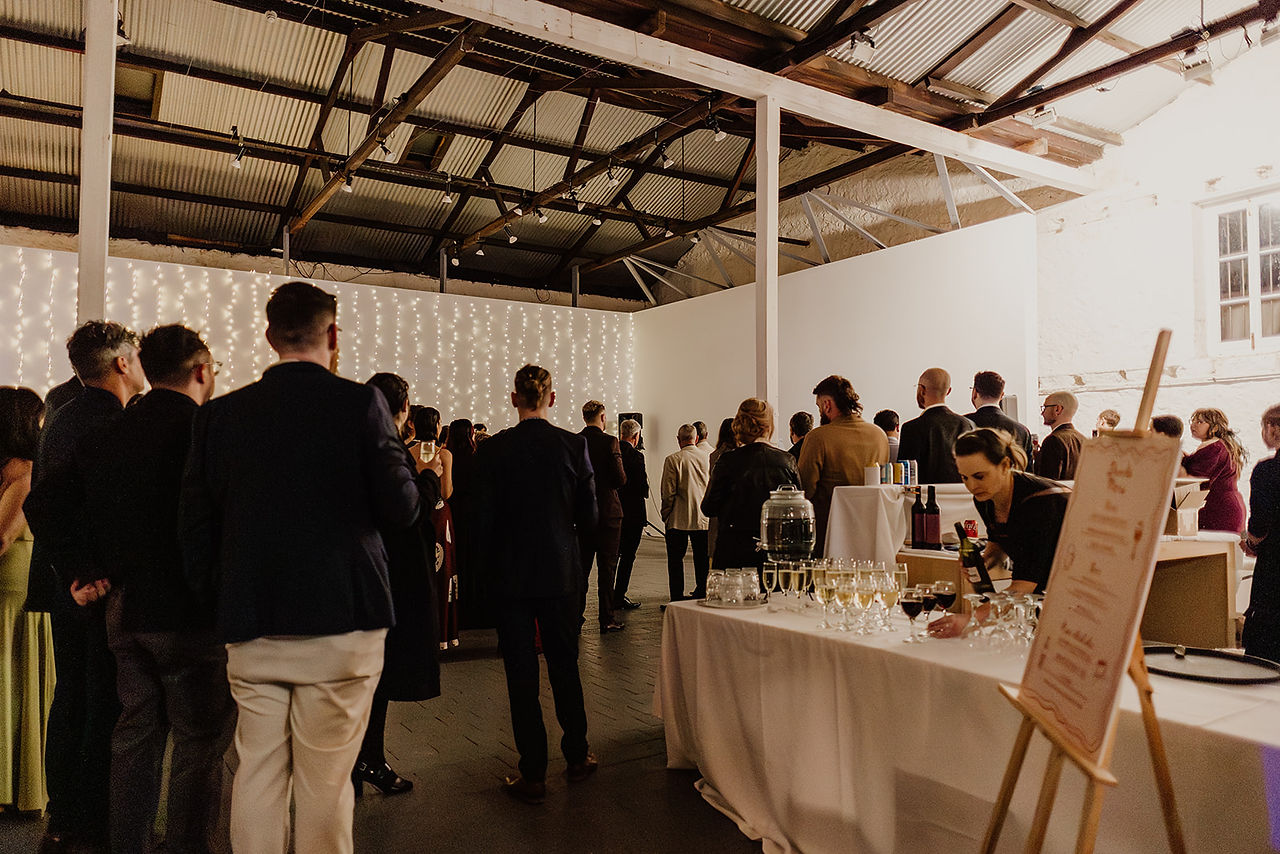 The wedding guests are gathered inside the gallery space at Moore and Moore in Fremantle. 