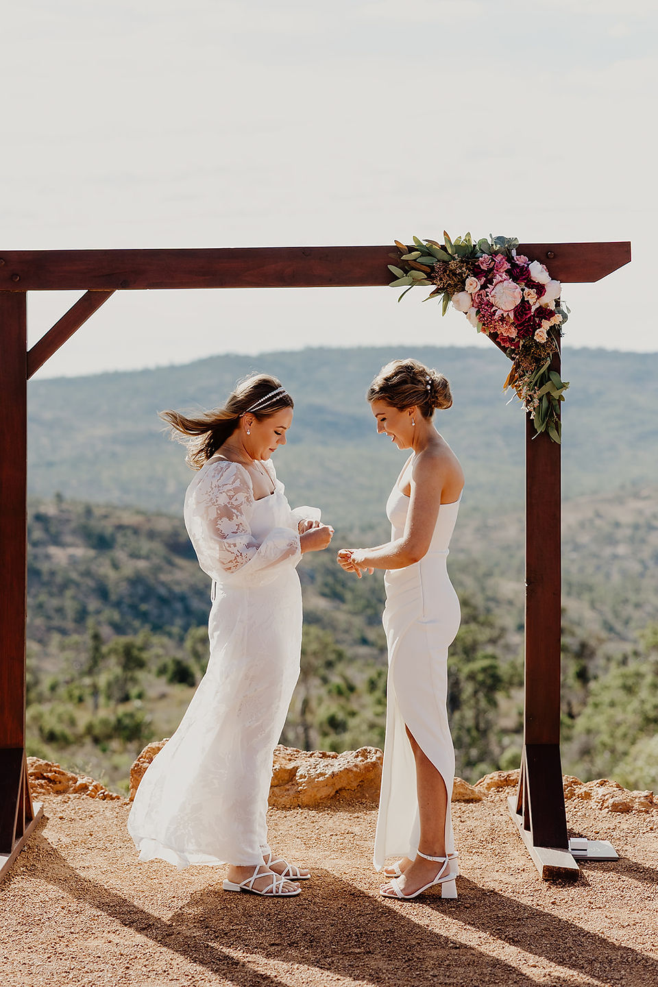 A bride places a wedding ring on her brides wedding finger during their wedding ceremony at Anderson Point in the Perth Hills
