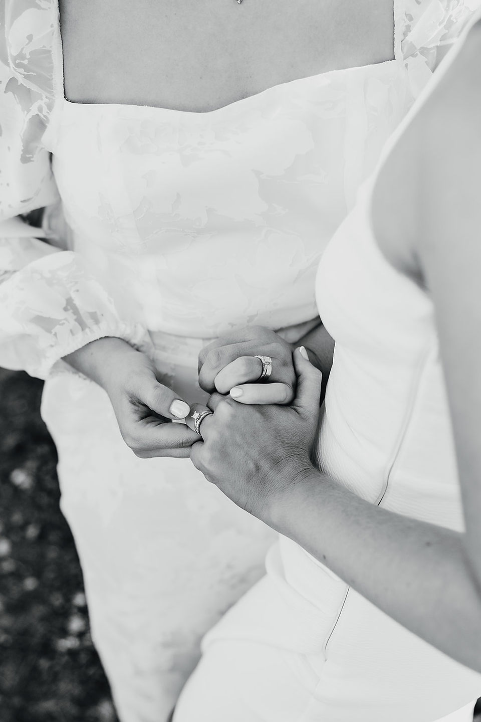 Two brides hold each other's hands. They wear white dresses and hold bouquets in the Australian bush at Anderson Point in the Perth Hills