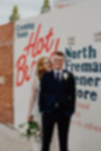 A bride and groom stand in front of the iconic Hot Bread sign in North Fremantle