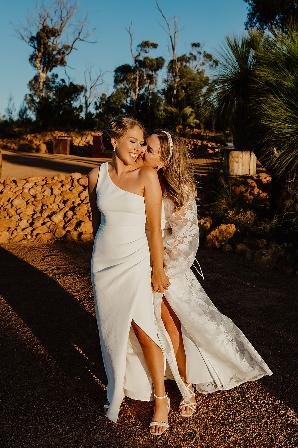 Two brides embrace as they look at the sunset at Anderson Point wedding venue in the Perth Hills.