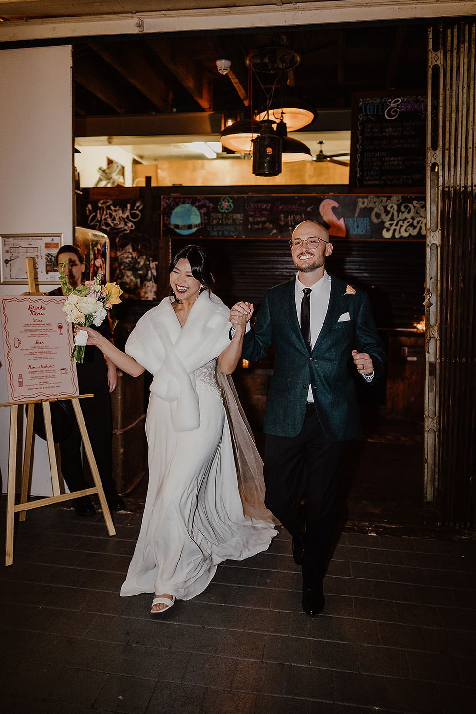 A smiling bride and groom enter their wedding reception at Moore and Moore in Fremantle