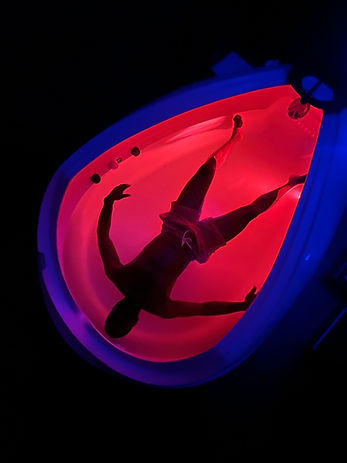a man floats in a red lit float tank