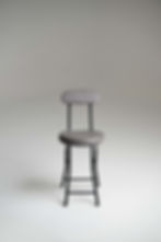 Grey padded bar stool with black metal legs in a studio