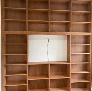 Empty wooden grid shelving unit with a central cutout for a television