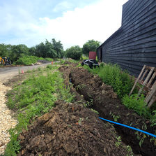 Blue pipes forming T-junction with couplings in soil.