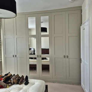 Built-in cream bedroom wardrobe with mirrored center doors