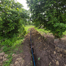 Blue pipe connected to cylindrical irrigation component in trench