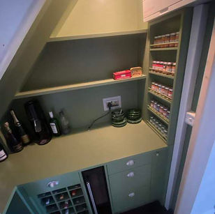 Under-stairs storage nook designed with shelves and built-in drawers