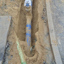 Blue pipe in trench near vehicle with coiled piping