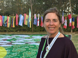 Angie Ferrazzini, fundadora de Sabe la Tierra, posa en la foto frente a todas las banderas que componen la Asamblea General de la World Farmer Markets Coalition